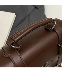Detail of reinforced leather handle with silver metal D-rings on dark brown handbag