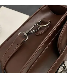 Detail of dark brown leather handbag featuring matte gunmetal hardware hooks and neat stitching