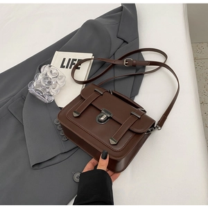 Close-up of vintage dark brown leather messenger bag with silver twist lock and handle