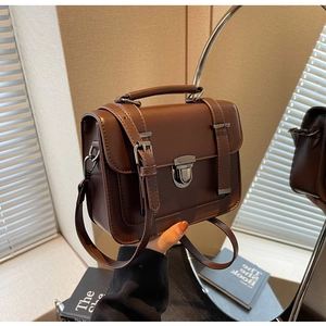 Close-up of a vintage brown leather satchel with metal buckle and top handle details