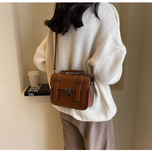 Detail of vintage brown PU leather crossbody bag with silver buckle on a model