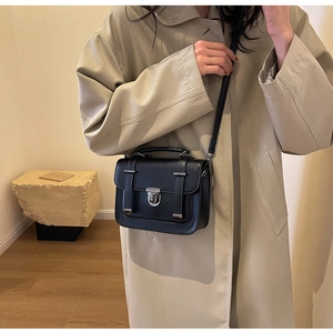 Detail view of the black matte leather flap and silver twist lock on the crossbody bag
