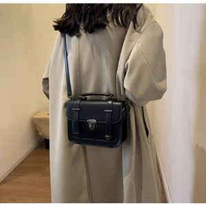 Detail of a black vintage crossbody bag worn with a beige trench coat for an elegant look