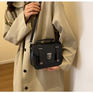 Classic black leather crossbody bag styled with a beige trench coat for a vintage look