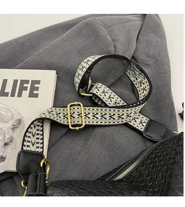 Détail de la bandoulière tissée réglable avec boucles dorées sur un sac à bandoulière noir
