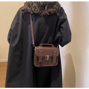 Brown vintage crossbody bag with silver buckle shown on shoulder for daily use