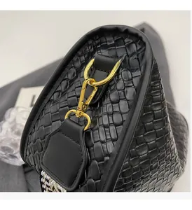 Détails du sac noir tressé avec anneaux dorés brillants et bandoulière à motifs géométriques