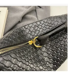 Détail de la fermeture éclair dorée sur le sac à main noir avec texture tressée