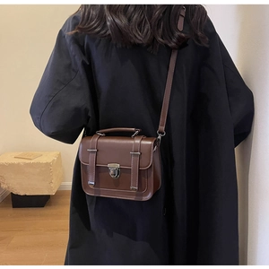 Detailed back view of a brown vintage leather crossbody bag with top handle on model