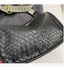 Détail du sac à bandoulière en cuir tressé noir avec texture fine et sangle en tissu doux