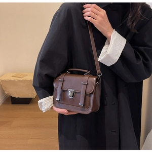 Detail of dark brown vintage crossbody bag with silver clasp and buckle accents