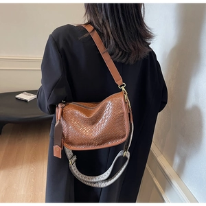 Détail d'un sac demi-lune marron tressé avec bandoulière en cuir et sangle géométrique