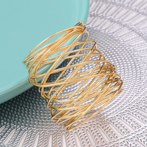 Golden woven wire napkin ring with hollow geometric mesh design on a ceramic plate