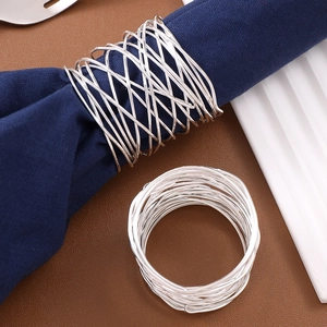 Close-up of silver wire-wrapped metal napkin rings on dark blue cloth napkins