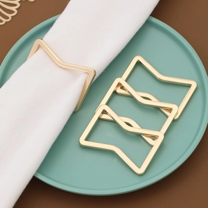 Close-up of four geometric gold napkin rings on a green plate and leather surface