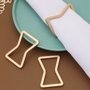 Close-up of golden matte geometric bow napkin rings on a mint green dining plate