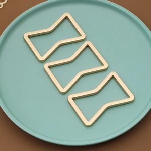 Three-piece set of gold geometric metal napkin rings with a sleek bow-shaped design