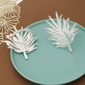 Silver leaf napkin rings set on blue plate with metallic texture and leaf vein detail