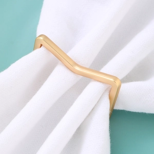 Detail of a matte gold geometric V-shaped napkin ring on white fabric background