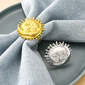 Golden and silver sun-shaped napkin rings set on elegant dinner table settings