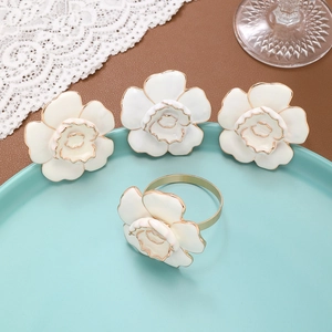 Lot de quatre ronds de serviette rose blanche avec bordure dorée sur assiette bleue