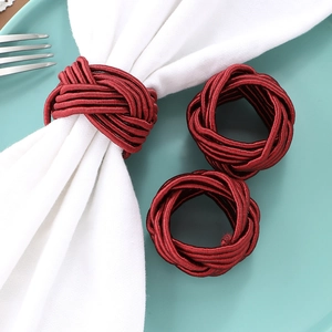 Handwoven burgundy cord napkin ring set on light blue plate for elegant dining