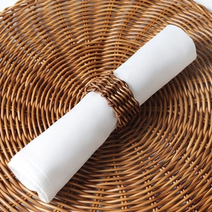 Brown woven rattan napkin ring with minimalist rustic design on matching table mat