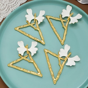 Set de 4 servilleteros de mariposa dorados con diseño de triángulo esmaltado blanco en plato
