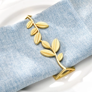 Golden leaf-shaped napkin ring on white plate with blue cloth napkin for wedding table decor