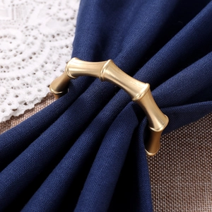 Rond de serviette en alliage de zinc style bambou doré sur tissu bleu marine et dentelle