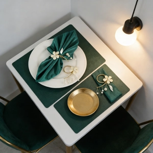 Detail eines Blumen-Serviettenrings mit Perlen auf grüner Satin-Serviette und Matte