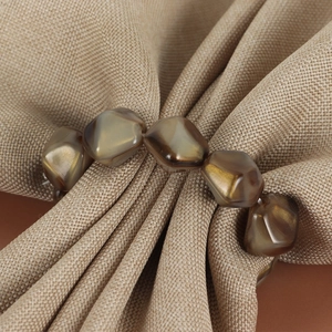 Stone textured amber bead napkin ring set on beige linen for elegant dining decor