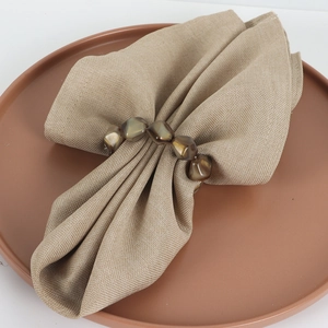 Handcrafted irregular beaded napkin ring in amber resin on natural linen napkin