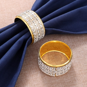 Golden napkin rings with crystal diamonds set on a navy blue fabric napkin decoration