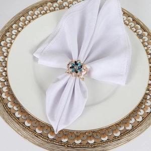 Close-up of golden flower napkin ring with blue rhinestones on a white plate