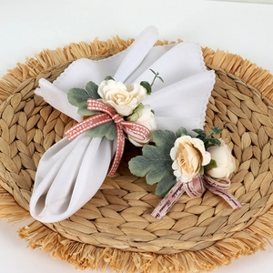 Rose flower napkin rings with pink ribbon and plaid bow on woven placemat decor