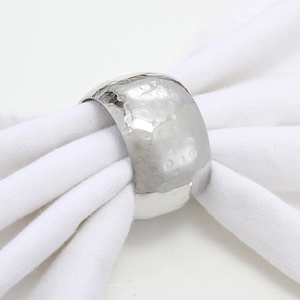 Silver hammered metal napkin ring with textured surface on a white fabric napkin