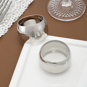 Silver hammered texture napkin rings for modern dining set displayed on white plates