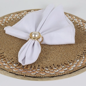 Elegant gold pearl napkin ring with large white pearl decoration on a white napkin
