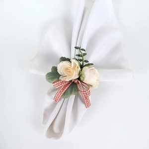 Detailed close-up of cream artificial roses and red checkered bow on a napkin ring