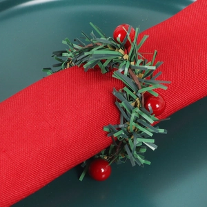 Détail d'un rond de serviette de Noël avec baies rouges et aiguilles de pin sur tissu