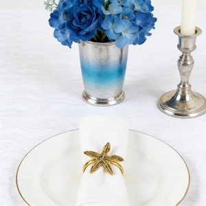 Detailed view of a golden starfish napkin ring on a white tablecloth with blue floral decor