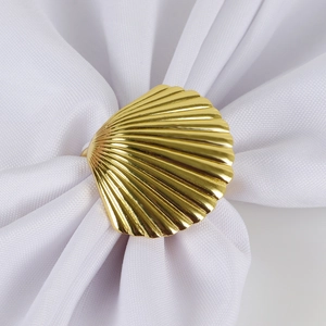 Golden scallop shell napkin ring on white fabric for elegant table decoration
