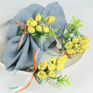 Detail of Easter napkin ring with yellow speckled eggs, green leaves and ribbon bow