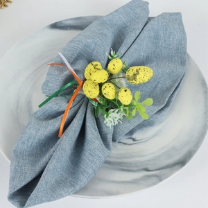 Detail of Easter napkin ring with yellow speckled eggs, greenery, and colorful ribbons