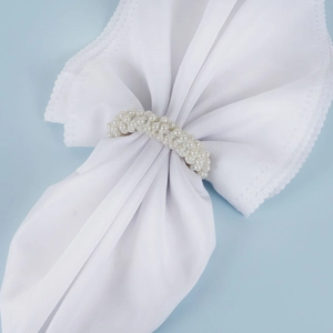 Elegant white pearl woven napkin ring with decorative wavy lace cloth on blue background