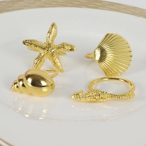 Detailed view of four gold ocean-themed napkin rings including starfish and seahorse