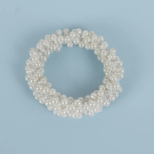 Close-up of white artificial pearl napkin ring with elastic beads on blue background