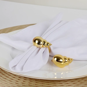 Macro detail of glossy gold conch napkin ring with shell texture on ceramic plate