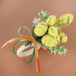 Detail of Easter napkin ring with speckled egg, artificial foliage and festive ribbons